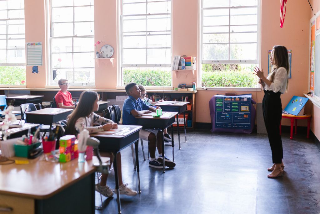 A teacher engaging students in a bright and active classroom environment.
